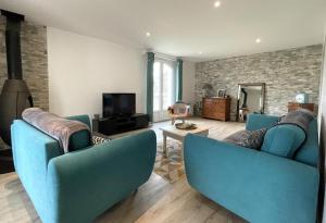 a living room with two blue chairs and a tv at Lajus fontaine in Livron