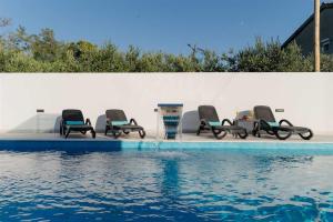 a group of chairs sitting next to a swimming pool at Villa Amare in Donji Zemunik