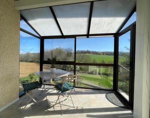 a glass extension of a house with a table and chairs at Cyralie in Asson