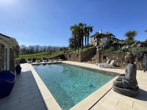 a swimming pool with a statue next to a house at Cyralie in Asson