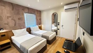 a bedroom with two beds and a laptop on a desk at Serenity Rooms in Përmet