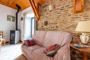 a couch in a living room with a stone wall at Gîte Gîtes de France 2/3 personnes à Malecombe in Cubières