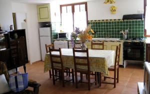 a kitchen with a table and chairs and a kitchen with green tiles at Villa la desirade in Cotignac
