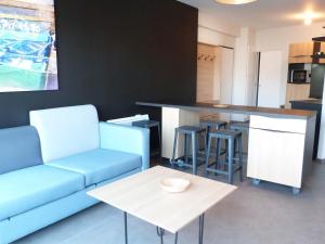 a living room with a blue couch and a kitchen at Appartement PMR 2 Chambres, Face Plage, Piscine, Balcon, Pour 6 Personnes, Animaux Admis - FR-1-194-222 in La Tranche-sur-Mer