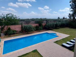 a swimming pool in a yard with two white chairs at Dar HAKIM piscine privée in Marrakesh