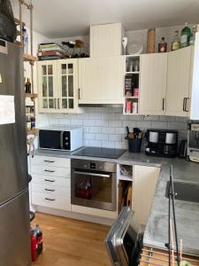 una cocina con armarios blancos y un aparato de acero inoxidable en Nacka, en Estocolmo