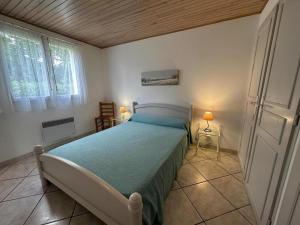 a bedroom with a bed with a green comforter and two windows at Rose in Biscarrosse