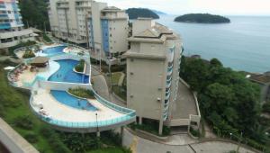 a building with a swimming pool next to the water at Porto Real Apartment Angra in Mangaratiba