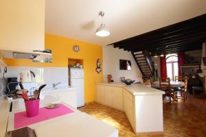 een keuken met gele muren, witte kasten en een tafel bij La foret in Aydie +24 foto's