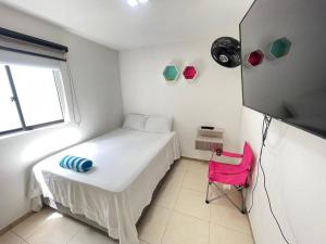 ein kleines Zimmer mit einem Bett und einem rosa Stuhl in der Unterkunft C311Espectacular Apartamento, Condominio Campestre in La Tebaida + 27 Fotos