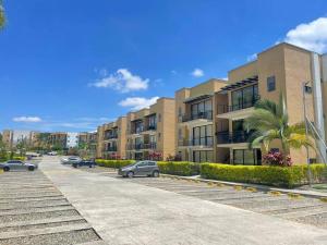 ein Parkplatz mit vor einem Gebäude geparkten Autos in der Unterkunft C311Espectacular Apartamento, Condominio Campestre in La Tebaida