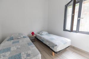 two twin beds in a room with a window at La maison de mon grand-père, appt la landaise du lac in Léon