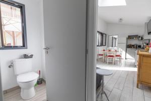a bathroom with a toilet and a kitchen with a table at La maison de mon grand-père, appt la landaise du lac in Léon