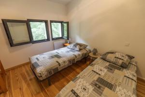 two beds in a room with two windows at La maison de grand-pere, appt cote lac in Léon