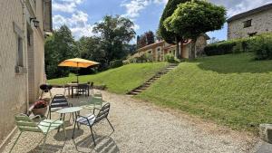 a patio with a table and chairs and an umbrella at Domaine de juriol - la demeure in Le Palais-sur-Vienne