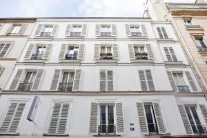 ein großes weißes Gebäude mit Fenstern und Fensterläden in der Unterkunft Magnifique appartement parisien in Paris