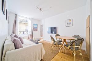 ein Wohnzimmer mit einer Couch und einem Tisch und Stühlen in der Unterkunft Magnifique appartement parisien in Paris