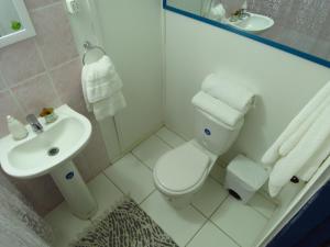 a white bathroom with a toilet and a sink at Hostal Benavente in Puerto Montt