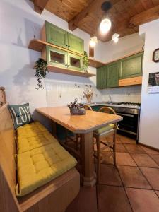 a kitchen with green cabinets and a wooden table at Appartamento Diamante - Ad un passo dalla Ciclabile in Auronzo di Cadore
