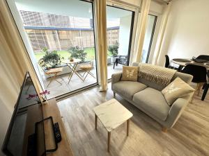 ein Wohnzimmer mit Couch und großem Fenster in der Unterkunft L'appartement de l'ermitage in Dax