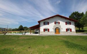 a white house with a red door and a grass field at Bordazarria in Juxue