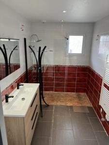 a bathroom with a sink and a shower with red tiles at La villa lou miqueou in Lit-et-Mixe