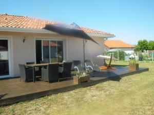 a wooden deck with chairs and an umbrella at La villa lou miqueou in Lit-et-Mixe