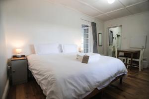 a large white bed in a room with a desk at Grootfontein Farm House in Beaufort West