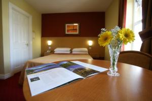 a table with a vase of yellow flowers and a book at Ballyliffin Hotel in Ballyliffin