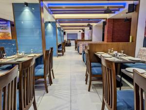 jadalnia z drewnianymi stołami i krzesłami w obiekcie Hotel Red Chillee Restro w mieście Silvassa