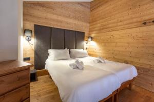 a bedroom with a large white bed with wooden walls at Résidence Les Balcons de Val Thorens & Spa in Val Thorens +37 photos
