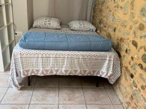 małe łóżko z kocem i poduszkami w obiekcie Studio à Le Boulou centre ville- pour 2 - petit prix- Juillet-aout réservation d'1 semaine minimum-check in 17-19h w mieście Le Boulou