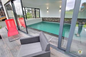 una piscina en una casa con una silla y una mesa en La roche mignonne, en Trébeurden