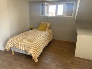 una piccola camera da letto con un letto con un cuscino verde di Chambre avec balcon dans charmante maison prêt d' aéroport d'Orly et proche paris a Villeneuve-le-Roi