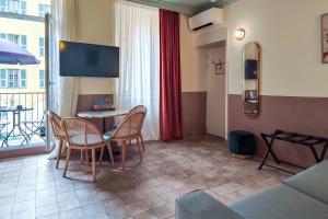 a living room with a table and chairs and a tv at Aparthotel AMMI Vieux Nice in Nice