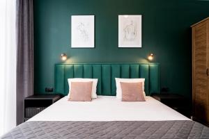 łóżko z zielonym zagłówkiem i 2 różowymi poduszkami w obiekcie Wawel Boutique Residence - Krakow Old Town w Krakowie
