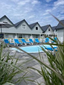 une piscine avec des chaises longues bleues devant un complexe hôtelier dans l'établissement Holiday House Sarbinowo, à Sarbinowo