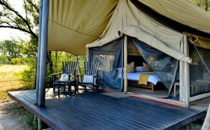 a tent with a bed and two chairs on a deck at Rhino Walking Safaris in Skukuza +64 photos