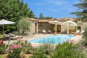 a pool with chairs and umbrellas in front of a house at Le Mas de Caroline in Gargas