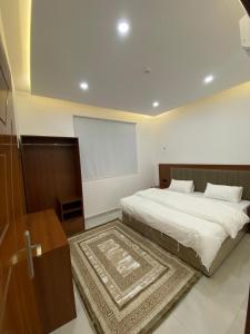 a bedroom with a large white bed with a rug at قصر أباهي للوحدات السكنية المفروشة in Al Nairyah