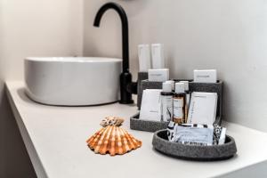 a bathroom counter with a sink and a counter top withbranded items at Elion Seaside Resort in Eretria