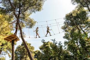 two people on a zip line in the trees at Sani Club in Sani Beach