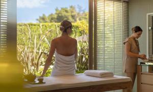 a woman standing in a bathroom looking out the window at Sani Club in Sani Beach