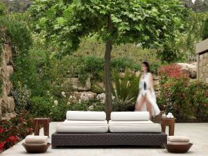 a woman walking past a white couch under a tree at Sani Club in Sani Beach