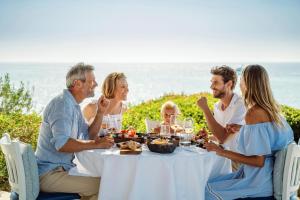 a group of people sitting around a table eating food at Sani Club in Sani Beach