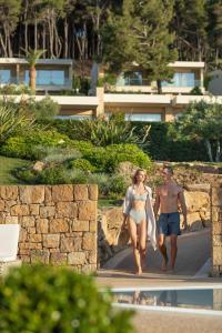 a man and a woman walking next to a swimming pool at Sani Club in Sani Beach