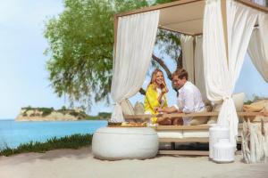 a man and woman sitting in a bed on the beach at Sani Club in Sani Beach