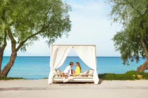 two people sitting on a bed on the beach at Sani Club in Sani Beach