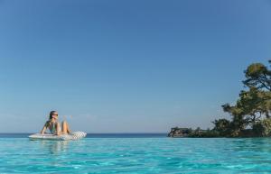 a woman is sitting on an inner tube in the water at Sani Club in Sani Beach