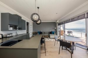 a kitchen and living room with a view of the ocean at Seasonsfind - The Sunset in Cape Town